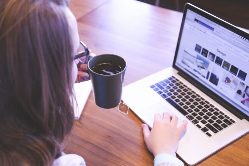 woman-working-at-a-laptop-and-drinking-a-cup-of-coffee