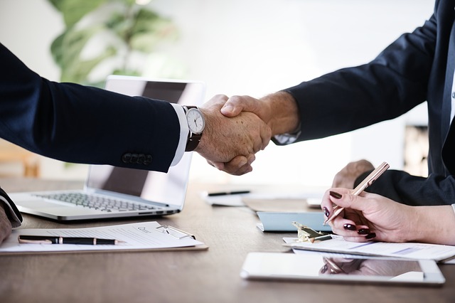 two-people-shaking-hands-over-a-busainess-desk