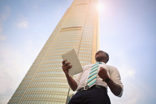 man-holding-a-tablet-device-with-large-building-in-the-background