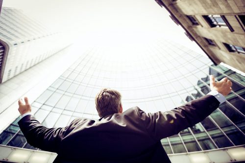 man-with-arms-open-looking-up-at-office-building-after-moving-offices