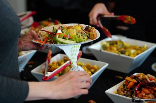 person-picking-food-from-a-buffet-table-with-salad