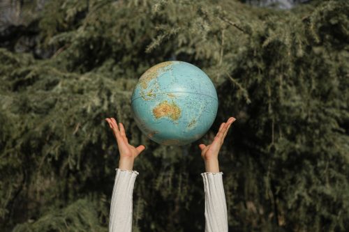 person-throwing-a-globe-in-the-air-with-trees-in-the-background