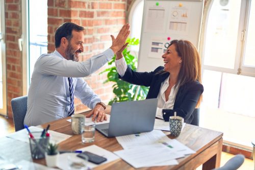 two-workers-high-fiving-at-a-desk