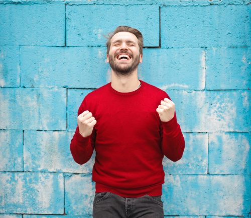 man-in-red-jumper-smiling-and-cheering