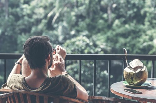 man-relaxing-on-a-balcony-with-his-feet-up