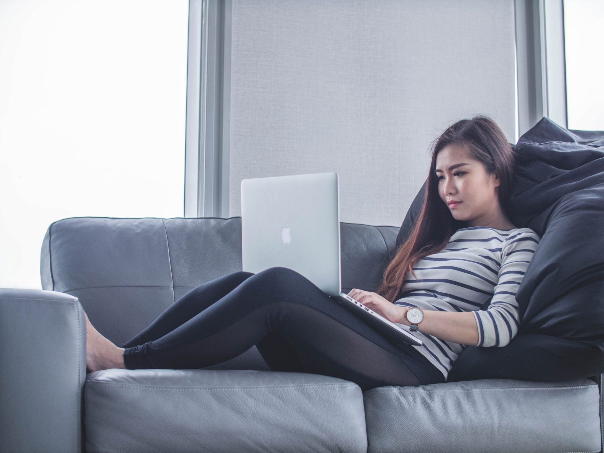 woman-lying-down-on-a-sofa-working-on-a-laptop