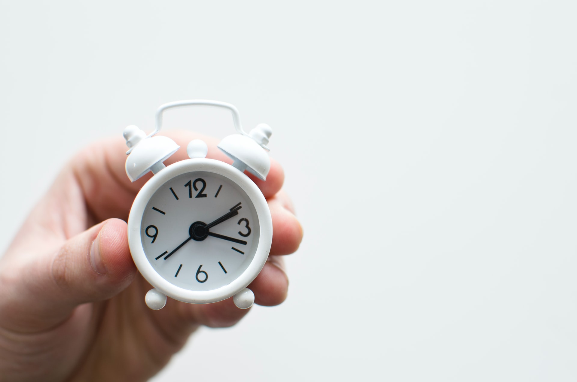 hand-holding-a-small-white-alarm-clock