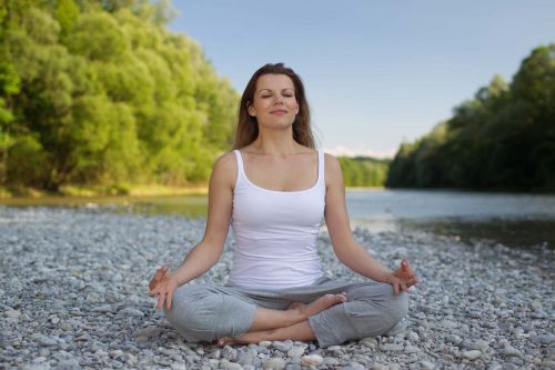 woman-meditating-on-a-white-stoned-beach-looking-at-peace