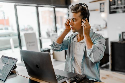 man-sitting-at-a-computer-listening-with-headphones