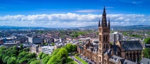 an-aerial-shot-of-glasgow-showing-a-cathedral-and-rolling-clouds