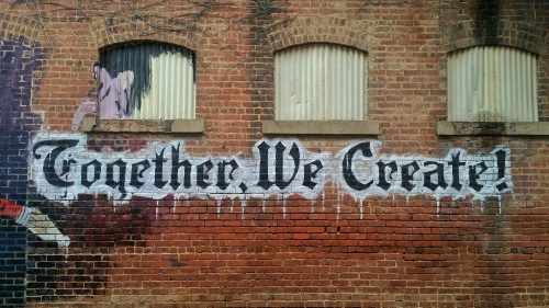 an-image-of-an-old-building-with-graffiti-on-the-side-saying-together-we-create