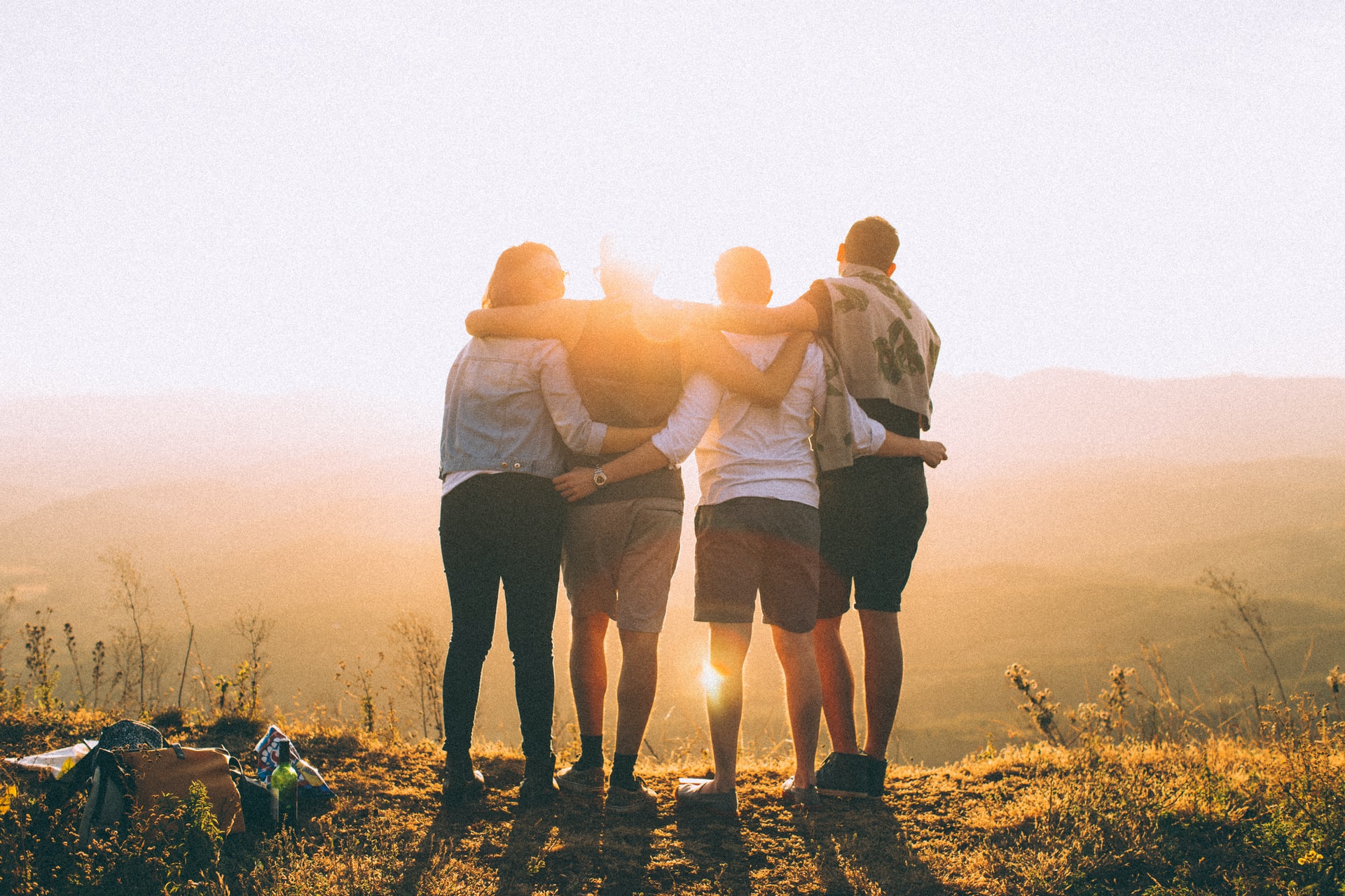 four-people-standing-on-a-hill-facing-away-with-the-sun-glaring