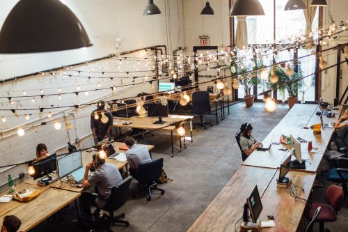 high-up-shot-of-an-office-space-with-individuals-working-on-computers-on-wooden-tables