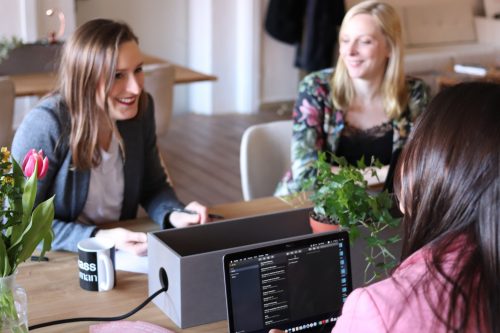 three-women-working-at-a-desk-looking-happy-and-smiling