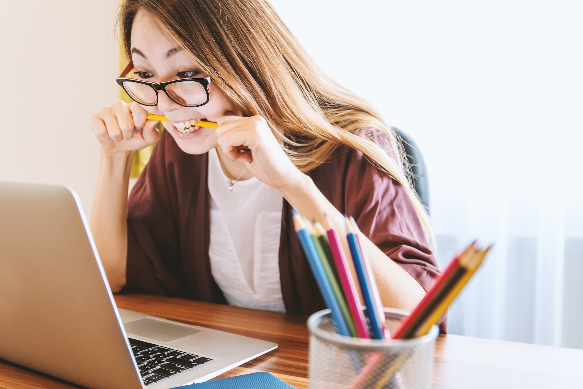 woman-biting-pencil-while-sitting-on-a-chair-in-front-of-a-computer-during-daytime