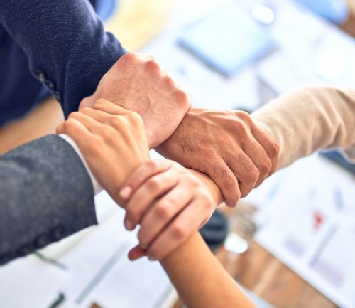 four-people-with-interlocking-hands-at-a-business-meeting