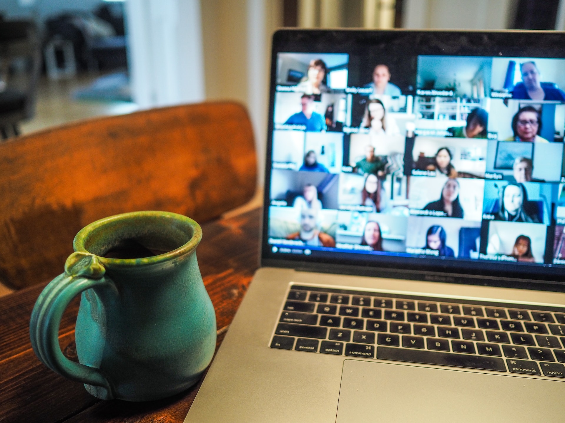 image-of-a-laptop-screen-showing-many-people-on-a-Zoom-meeting-next-to-a-cup-of-coffee