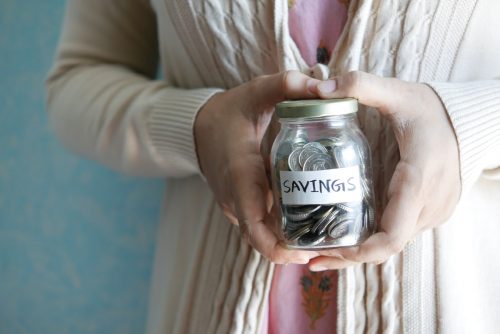 a-person-holding-a-jar-with-coins-inside-with-a-label-that-says-savings