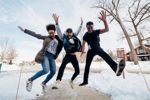 three-people-jumping-smiling-and-waving-their-arms