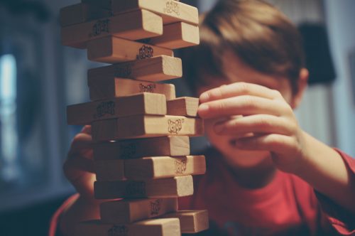 boy-playing-jenga-trying-to-move-a-brick-out-of-a-tricky-position