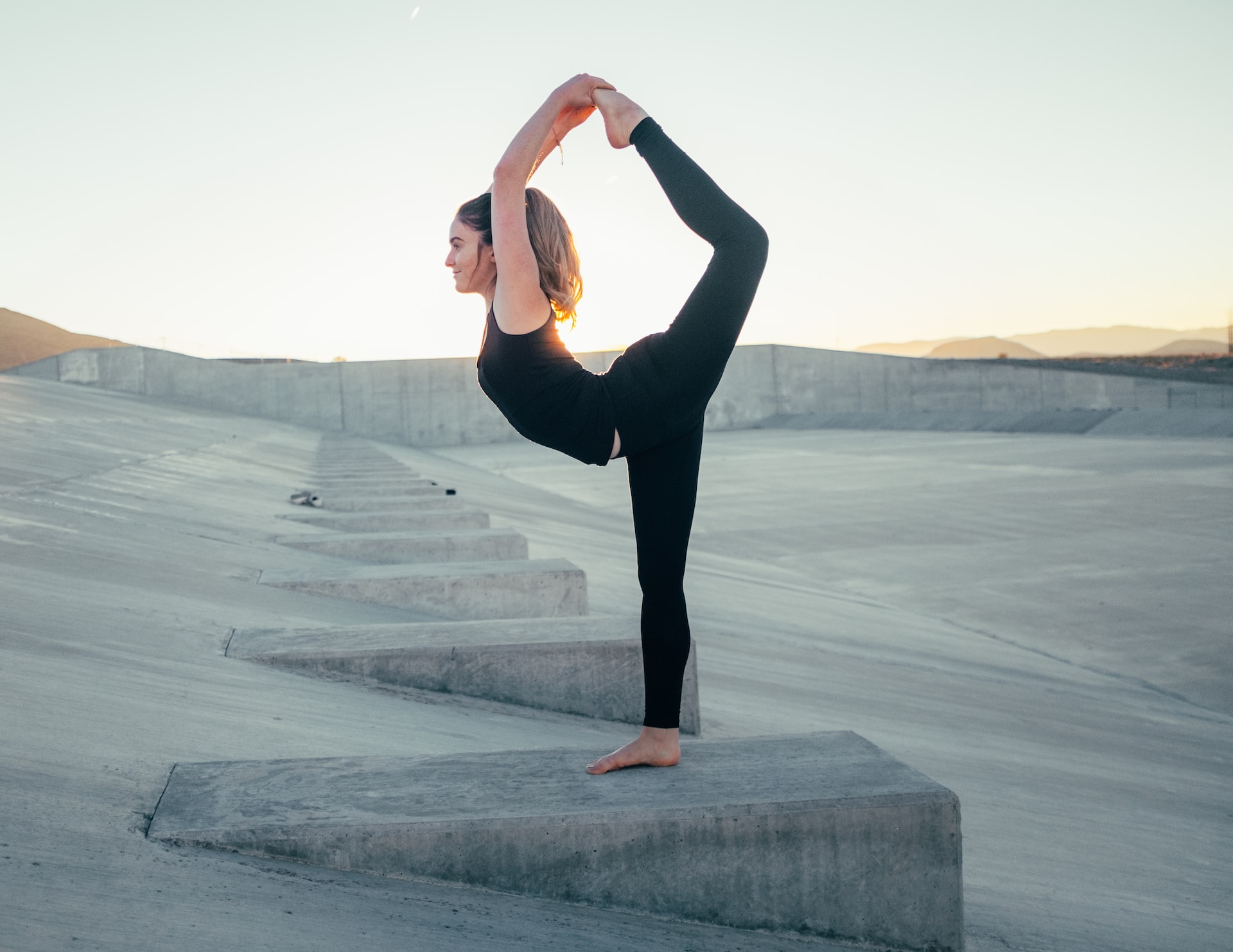 woman-outside-doing-a-flexible-yoga-pose-with-her-leg-bending-back-upwards-towards-her-head