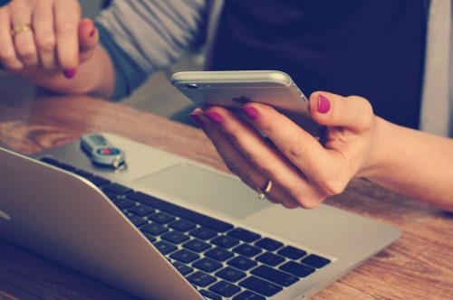 close-up-shot-of-a-person-holding-a-smart-phone-above-a-laptop