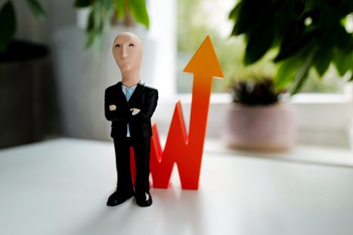 image-of-a-small-businessman-figurine-standing-next-to-an-arrow-going-upwards