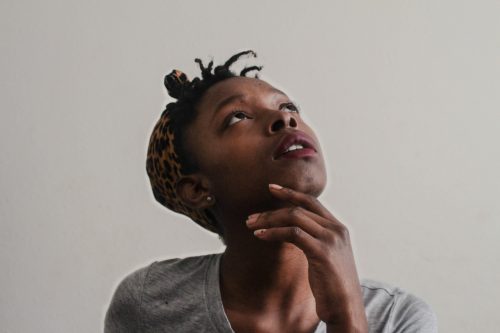 shot-of-a-woman-looking-up-with-her-hand-on-her-chin-thinking