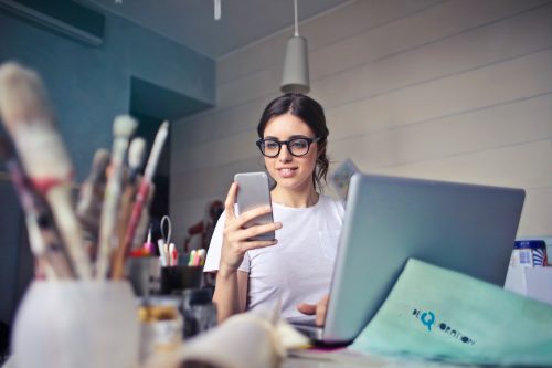 woman-looking-at-her-phone-whilst-working-looking-happy