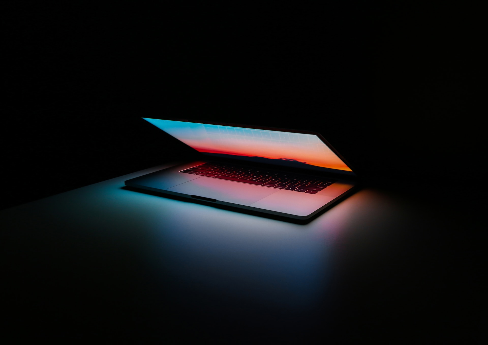 dark-image-of-a-laptop-almost-closed-and-a-faint-light-emitting-from-it