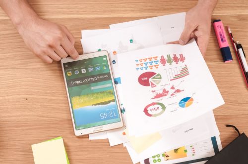 top-down-photograph-of-someone-looking-at-data-on-paper-with-a-smartphone-to-the-side