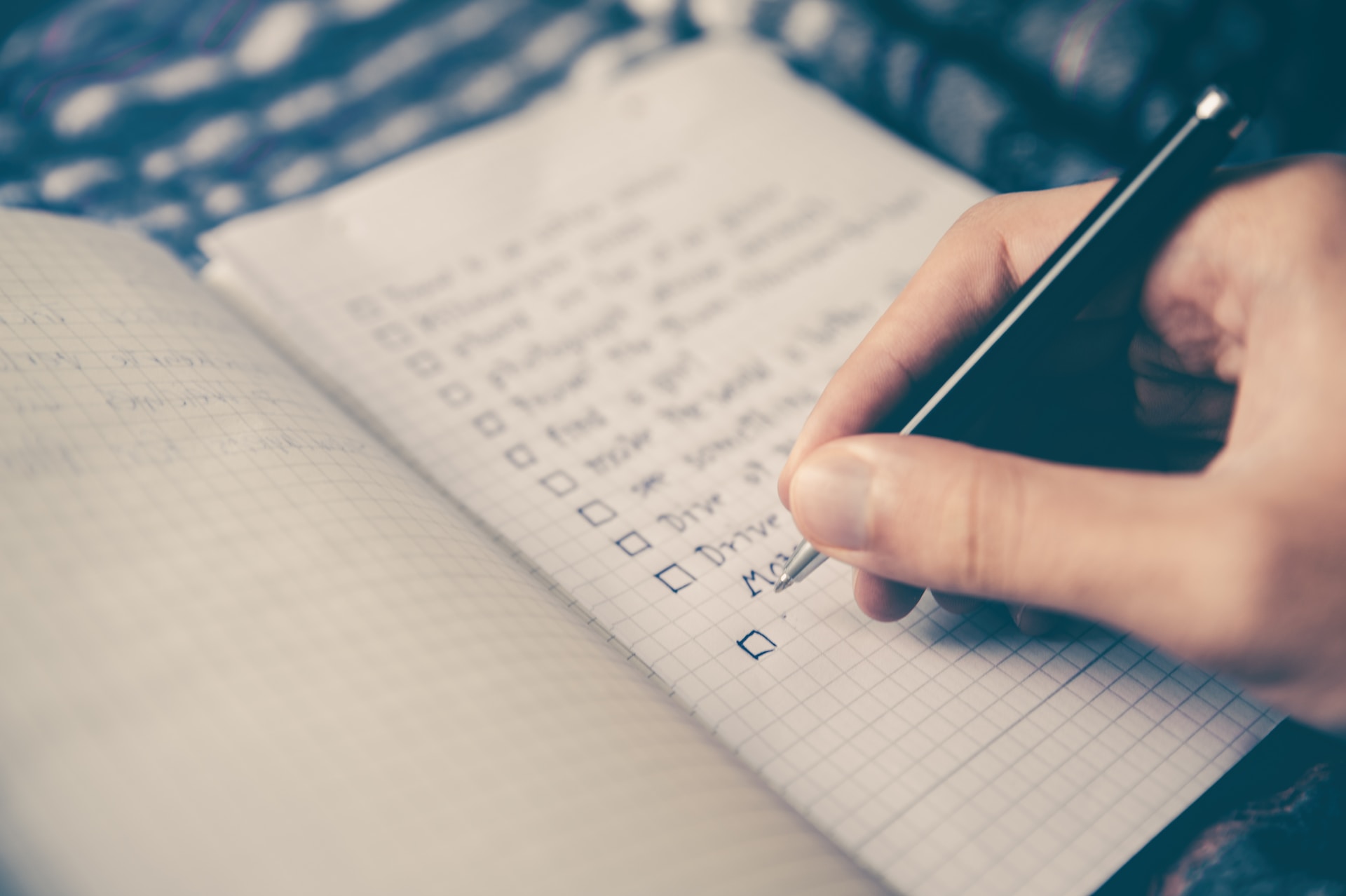 close-up-shot-of-someone-writing-a-checklist-and-plan-in-a-notebook