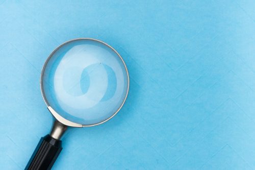 close-up-shot-of-a-magnifying-glass-against-a-blue-background