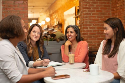four-women-sitting-around-a-table-talking