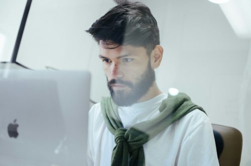 image-of-a-man-quietly-working-behind-some-glass-on-a-mac-computer