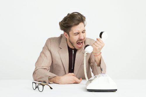 man-shouting-into-a-white-phone-arguing