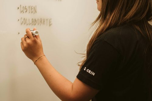 woman-writing-on-a-white-board-with-the-words-listen-and-collaborate-visibly-written